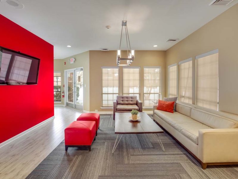 This image showcases the spacious club room featuring the comfy sofas, elegant floor mat, large windows, and flat-screen TV that suitable for business meetings and gatherings.