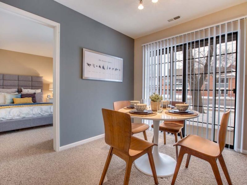 This image features the wooden dining table with window blinds overviewing outside scenery.