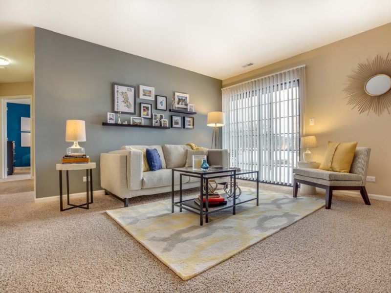 This image shows an expansive living room area with oversized windows with blinds.